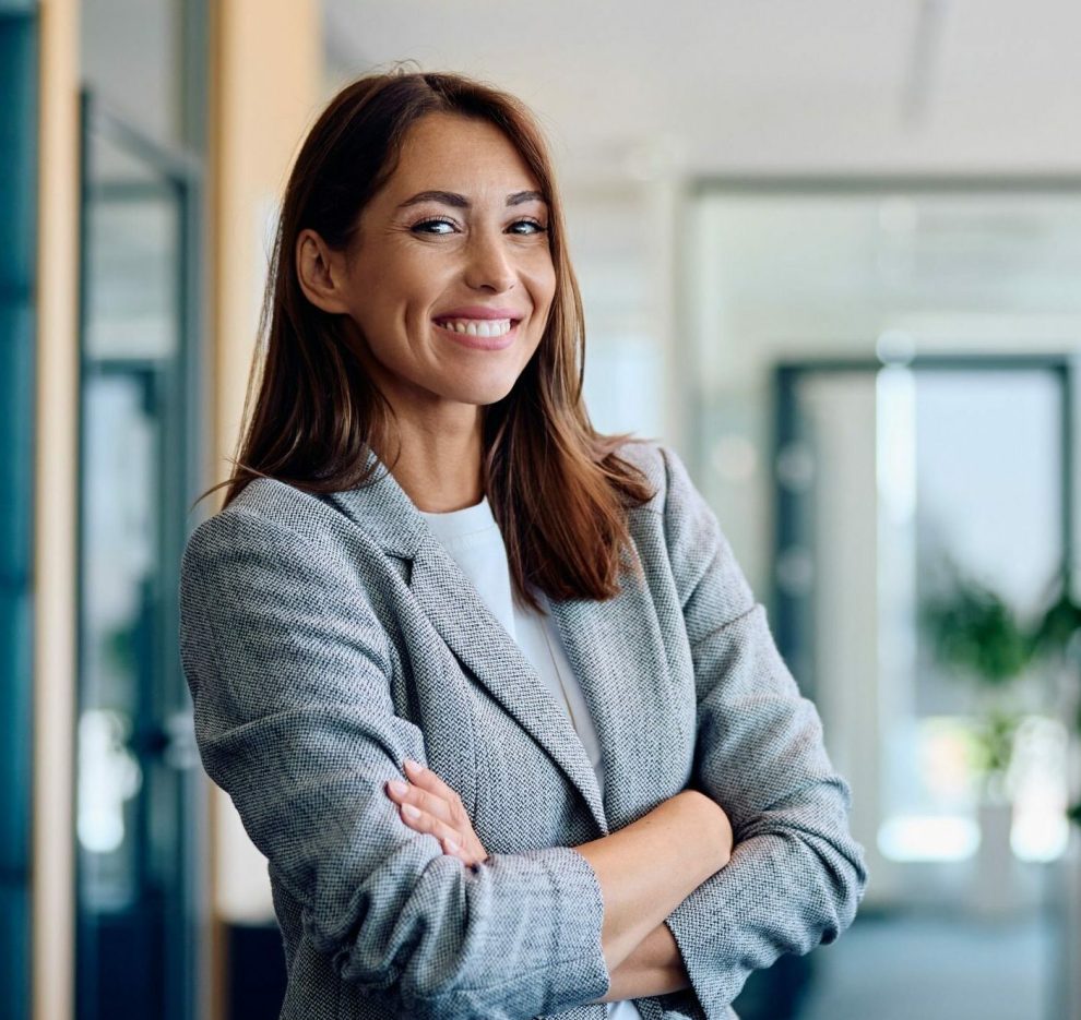 Young,Happy,Businesswoman,With,Arms,Crossed,Standing,Int,He,Office
